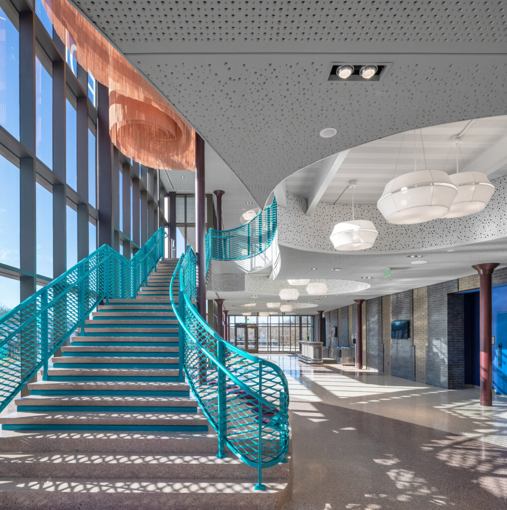 Custom teal blue expanded mesh railing in performing art center lobby.